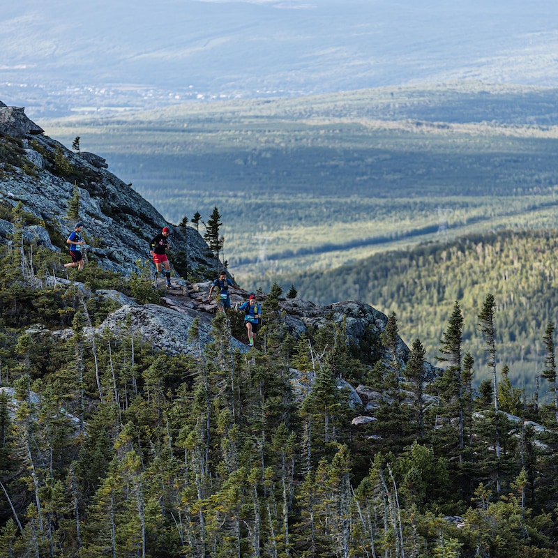 Des coureurs parcourent un sentier au sommet d'une montagne.