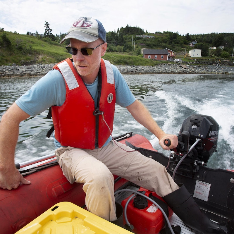 Pierre-Paul Bitton portant une veste de sauvetage conduit un bateau.