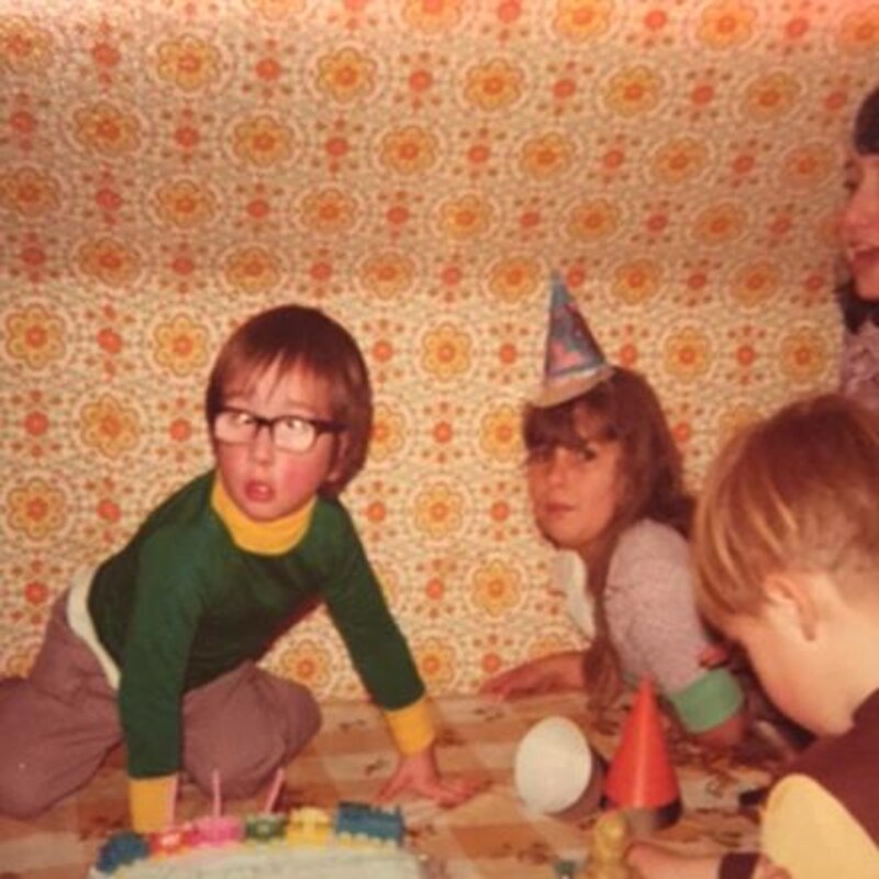 Tim Doucette, enfant, debout sur une table devant un gâteau d'anniversaire et entouré d'autres enfants.