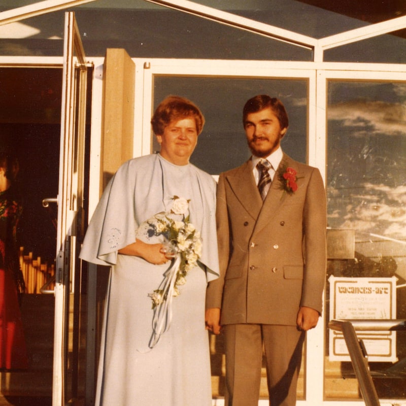 Un couple de mariés pose devant une église.