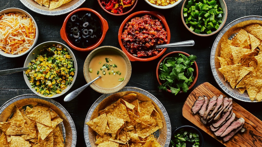 Des croustilles de maïs et des accompagnements à nachos sont servis dans plusieurs petits plats.