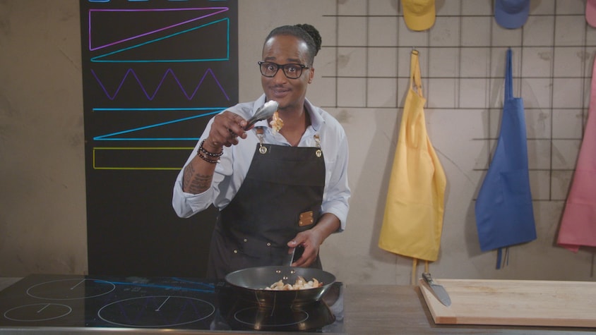 Une personne tient une crevette cuite entre les pinces de cuisson au-dessus d'une poêle.