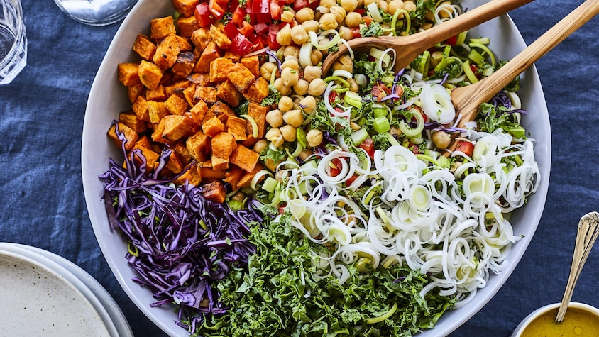 Salade colorée avec des poireaux hachés, des pois chiches, des poivrons rouges hachés, des patates douces et du choux rouge.