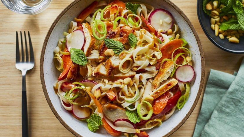 Un bol contenant la salade thaïe au poulet grillé et au poireau sur une table. 