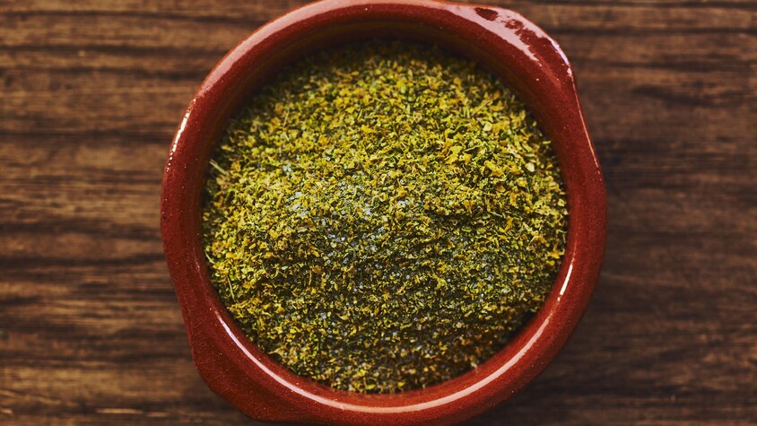 Le sel aromatisé dans un petit plat de terre cuite sur un comptoir de bois. 