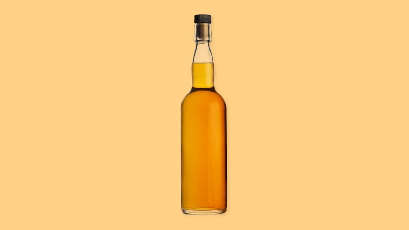 Une bouteille d'alcool brun sur un fond jaune.