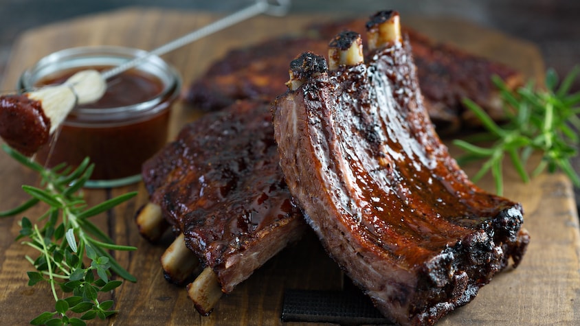 Des côtes levées avec une sauce BBQ sur une planche de bois.