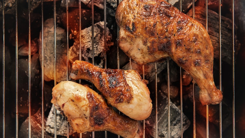 Des cuisses de poulet qui grillent sur du charbon de bois.