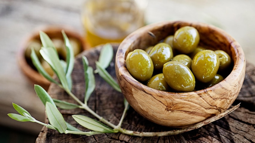 Des olives vertes dans un petit bol en bois.