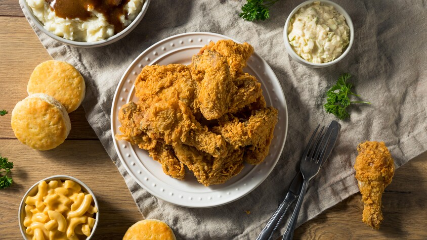 Une assiette de morceaux de poulet frit, un bol de purée de pommes de terre, petits pains et salade de macaroni.
