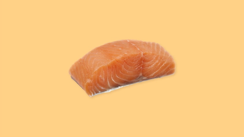 Un pavé de saumon cru sur un fond jaune.