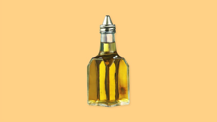 Une bouteille de vinaigre sur un fond jaune.