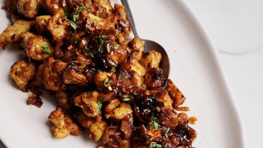 Dans un plat de présentation se trouve du tofu à l'échalote caramélisée.