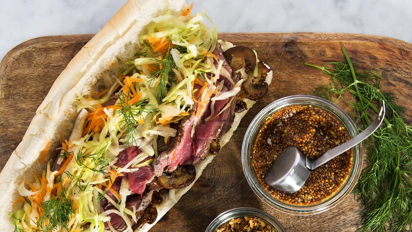 Sandwich au bœuf, aux champignons et au chou mariné ouvert sur une planche.