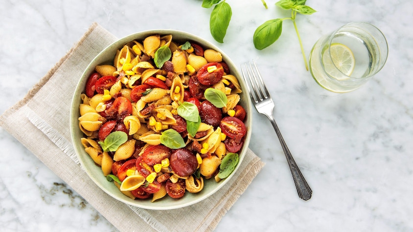 Un bol de coquilles au chorizo, aux tomates cerises et au maïs.