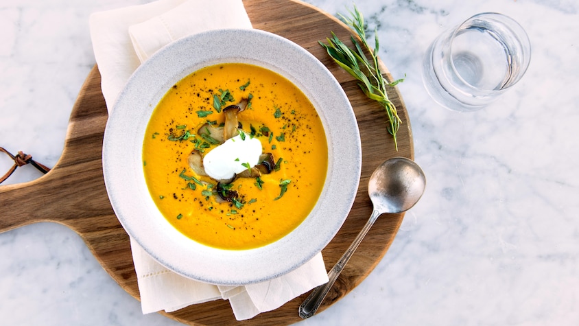 Un bol de potage aux carottes et garniture de pleurotes.