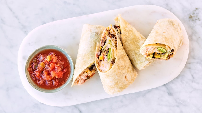 Quatre moitiés de burritos au bœuf dans une assiette avec de la salsa.