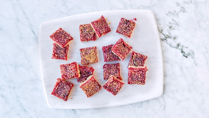 Seize carrés aux framboises et à la noix de coco dans une assiette.