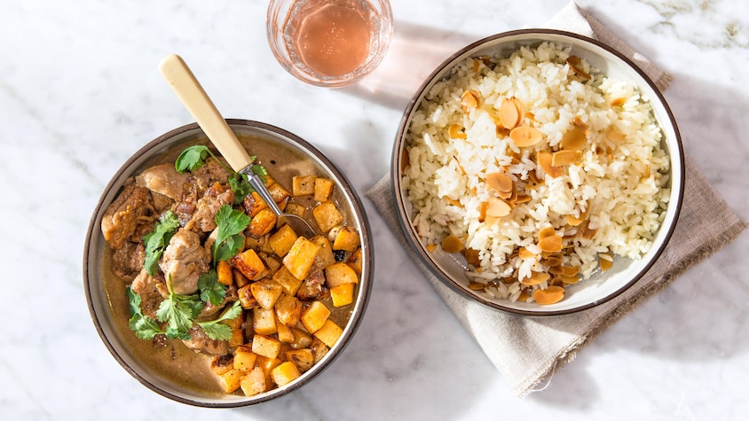 Un plat contenant du riz et des amandes rôties et un autre plat contenant du poulet et des cubes de rutabaga. 