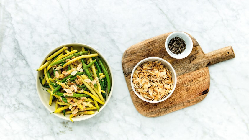 Un bol rempli d'haricots verts et jaunes garnis d'amandes.