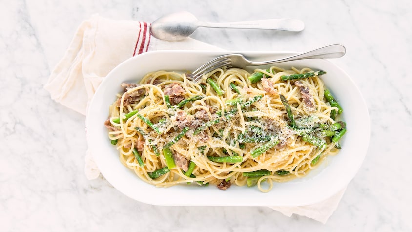 Du spaghetti carbonara aux asperges et au prosciutto dans une assiette de service.