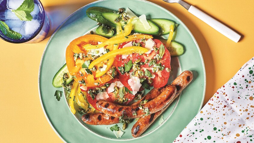 Des merguez accompagnées de légumes dans une assiette.