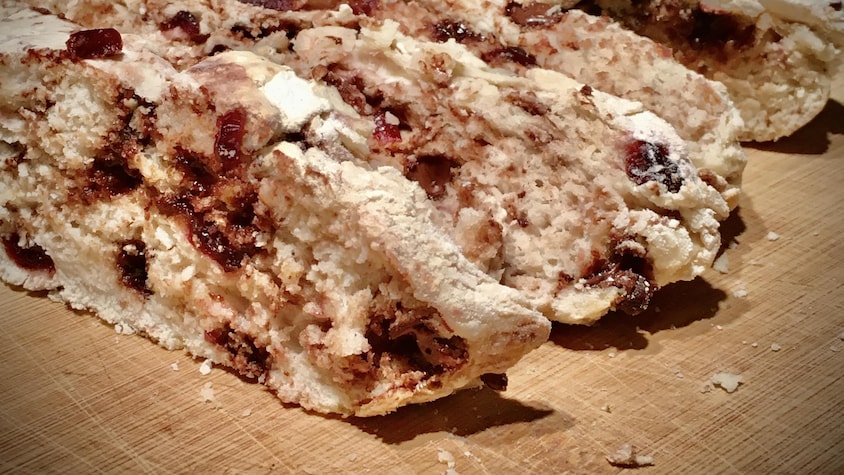 Un pain aux canneberges tranché sur une planche de bois.