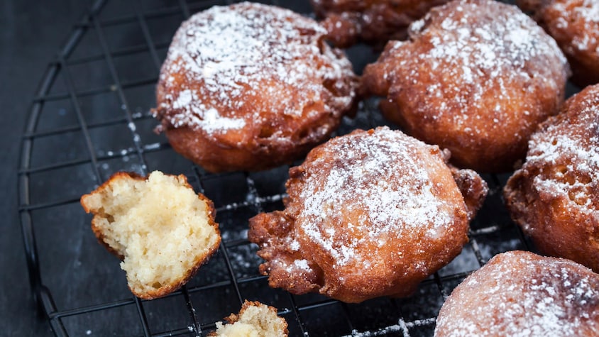 Des beignets aux pommes sur une grille recouverts de sucre.