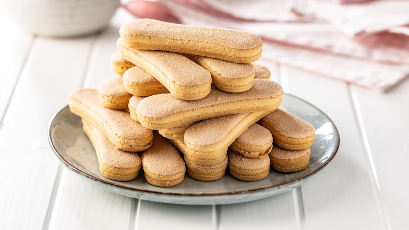 Des biscuits doigts de dame empilés les uns sur les autres en pyramide sur une assiette ronde.