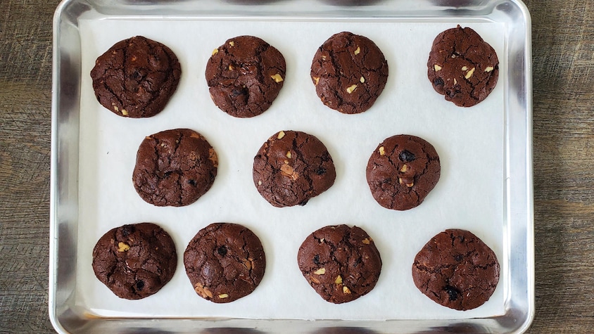 Une plaque de cuisson avec des biscuits au chocolat cuits.