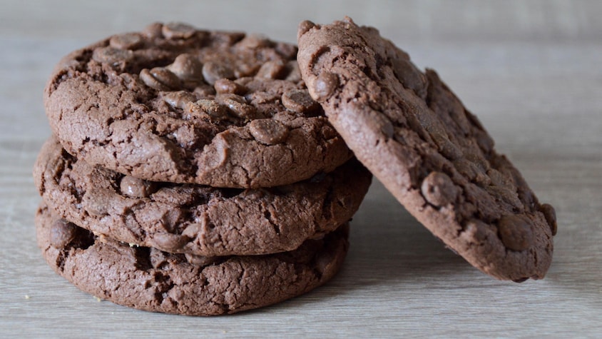 Quatre biscuits double chocolat sur une table.