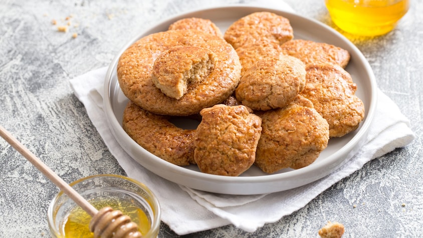 Des biscuits au miel dans une assiette et du miel dans un bol juste à côté.