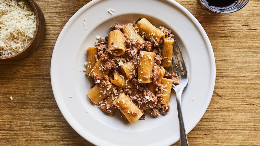 Une assiette de pâtes à la sauce bolognaise avec du fromage râpé.