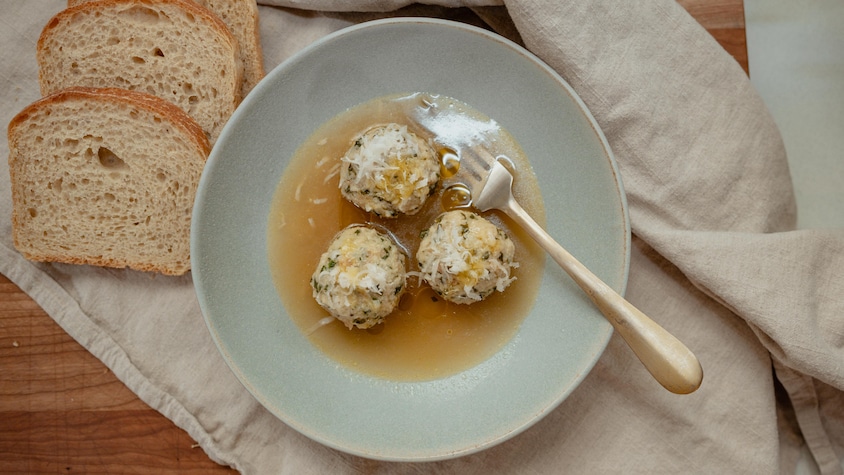 Trois boulettes dans un bouillon de légumes avec du parmesan.