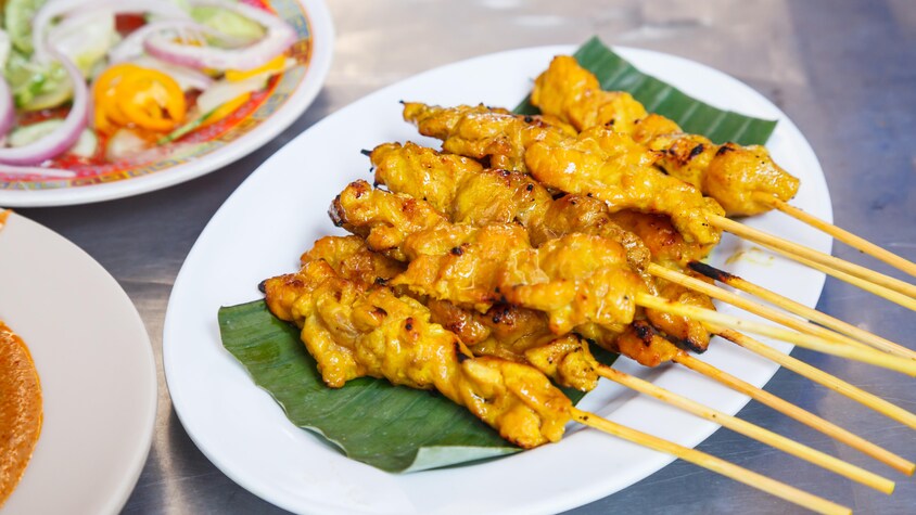 Des brochettes de porc cuites sur une feuille de bananier.