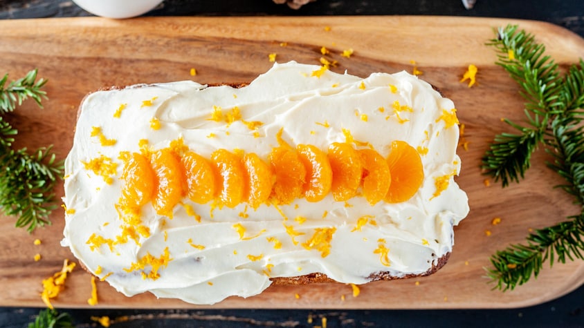 Cake aux clémentines et Grand Marnier avec son glaçage au fromage à la crème sur une planche de bois.