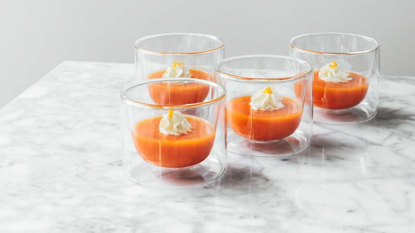 Des petits verres contenants des cappuccino de carottes garnis de crème fouettée à l’orange.