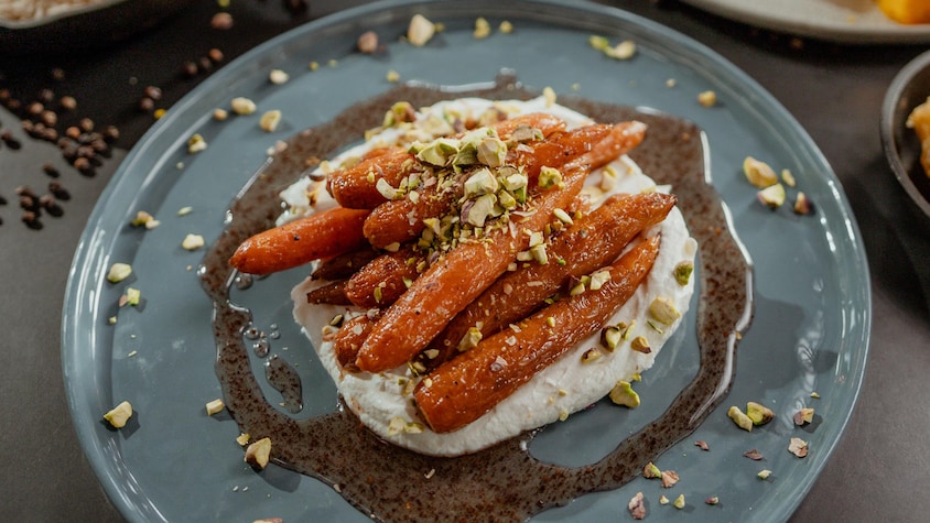 Plusieurs carottes glacées déposées sur du labneh dans une assiette.