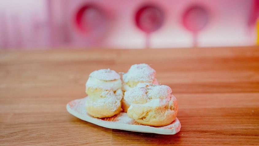 Quatre choux farcis de crème fouettée dans une assiette.