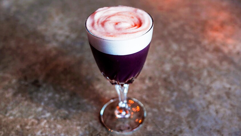 Un cocktail violet avec beaucoup de mousse.