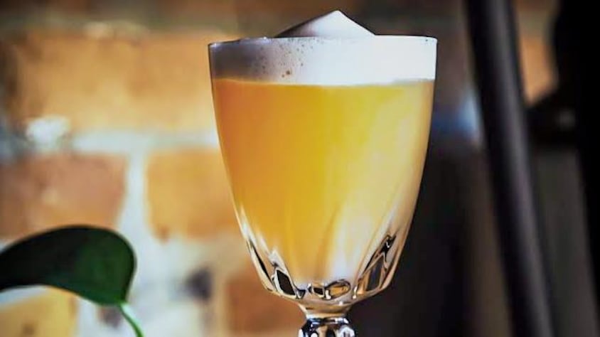 Un cocktail jaune dans un verre avec de la mousse.