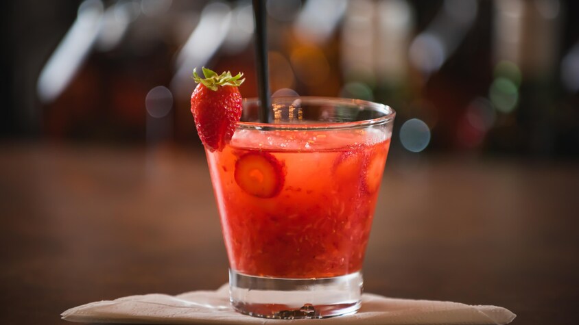 Un cocktail rouge décoré d'une fraise.