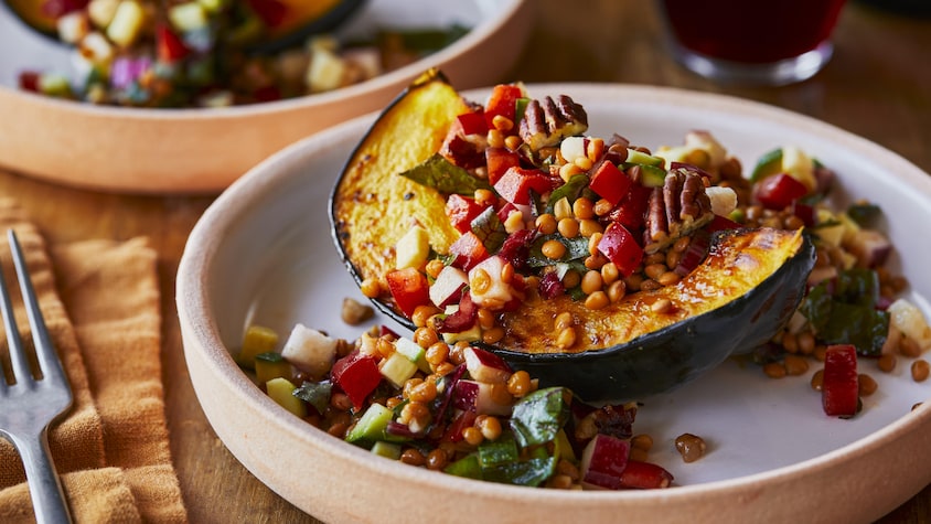 Une courge rôtie à la salade de lentilles dans une assiette.