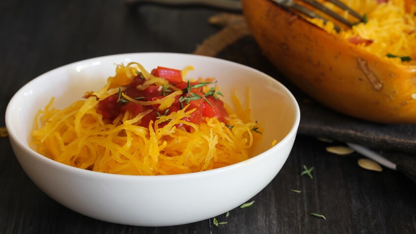 Un bol rempli de courge spaghetti avec un peu de sauce tomate.