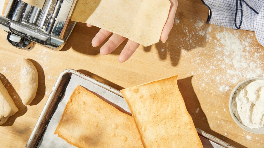 Les craquelins crus sortent de la machine à pâte et les craquelins chauds sont sur une plaque à cuisson.