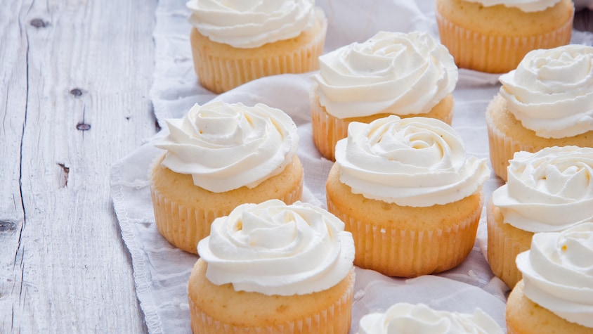 Neuf cupcakes garnis de crème au beurre.