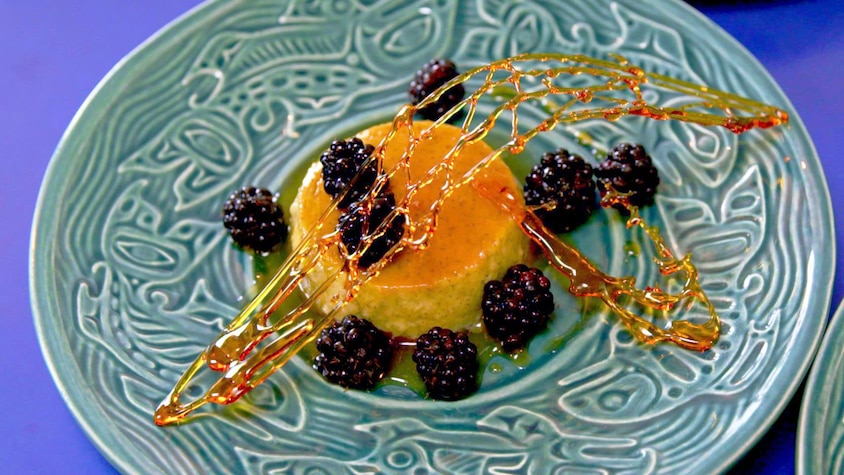 Une crème caramel recouverte de mûres dans une assiette.