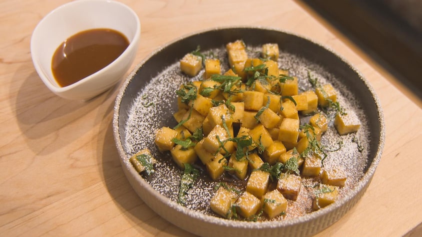 Des cubes de tofu dans une assiette accompagnés d'un bol de sauce.