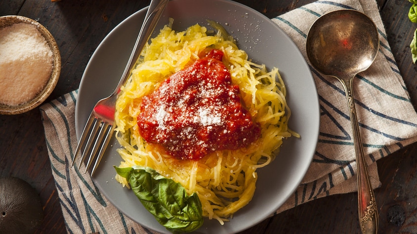 Une assiette de courge spaghetti recouverte de sauce tomate.