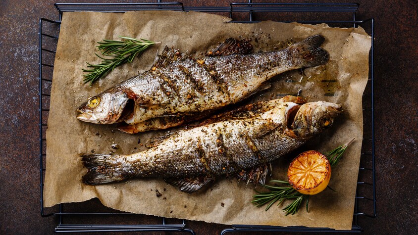 Deux poissons bien grillés sur un papier parchemin.